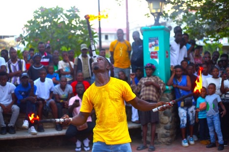 A performer pretends to get burned after attempting to put a lit torch in his mouth. Photo by Onz Chéry/ The Haitian Times
